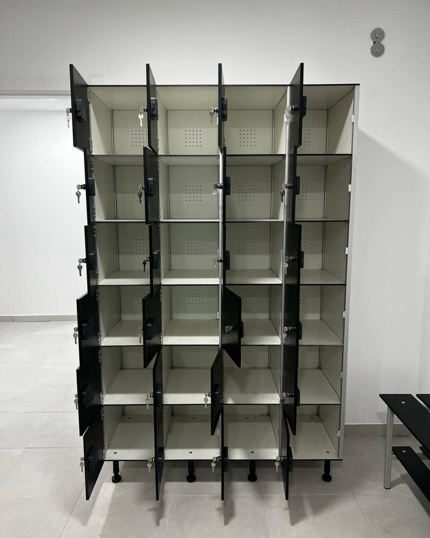Conjunto de taquillas fenólicas negras con cerraduras individuales en vestuario colectivo moderno con banco fenólico lateral