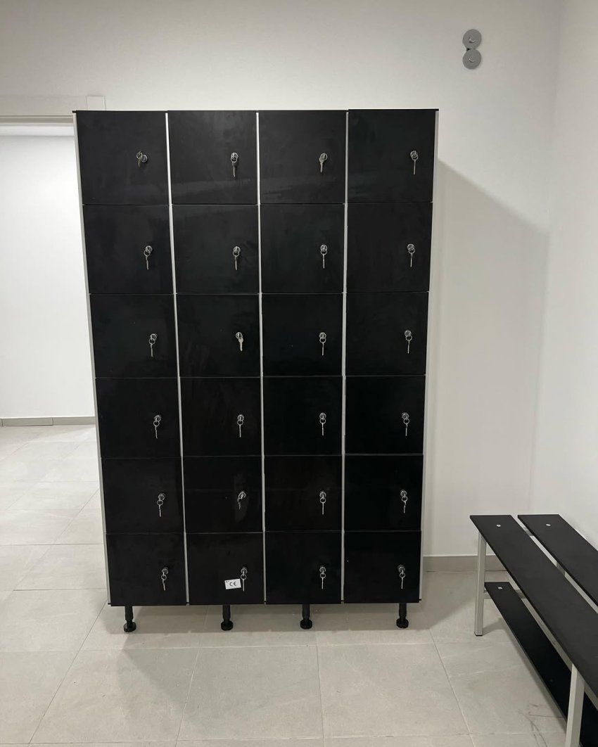 Taquillas fenólicas negras con cerraduras y banco fenólico en vestuario moderno de gimnasio o instalación deportiva